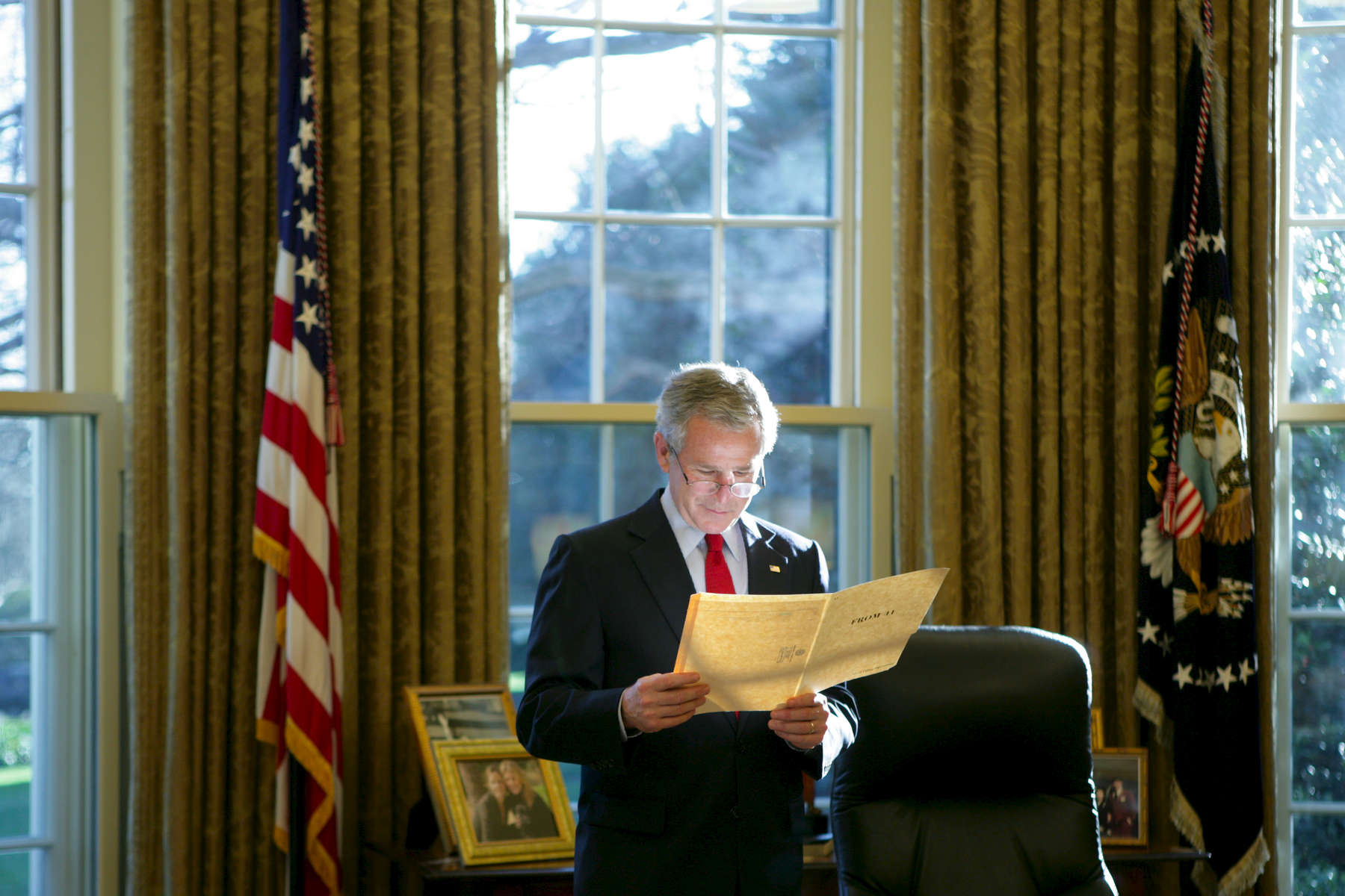 President Bush stands at his desk and reads a file between Meetings with Republican Members of the Senate. Oval Office. POW