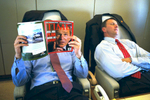 PRESIDENT BUSH DEPARTS FOR KANSAS CITY, MISSOURI. A staff member reads Time Magazine on Air Force One. President Bush's photograph is n the cover. A staff member sleeps.  Used in Bush Family Scrapbook June 1-June 20, 2002