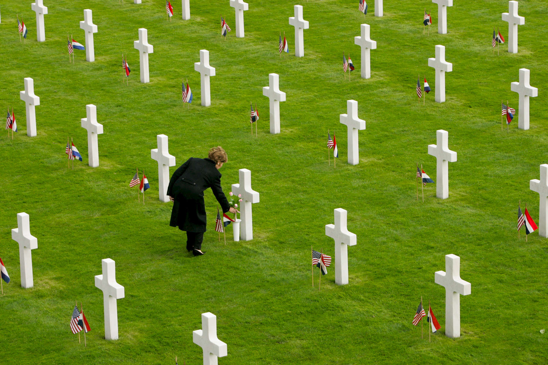 President Bush, Laura Bush: Netherlands American Cemetery and Memorial. Margraten, Netherlands.  Mrs. Bush lays flowers at the grave of Francis A. Pate, TEC 5, Illinois, from the 104th Division.