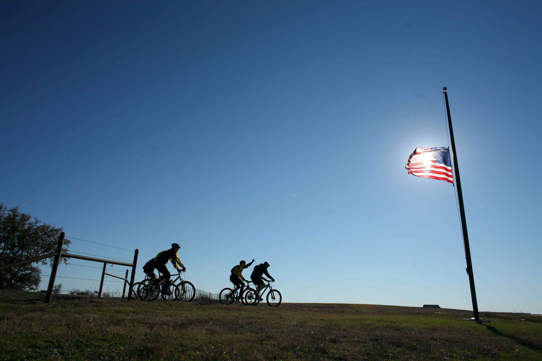 President Bush: Bike Riding with guests. Ranch, Crawford, Texas. American flag at half-staff on death of President Gerald R. Ford. Participants include: Mark McKinnon, Craig Savage and Kia Baskerville. POW