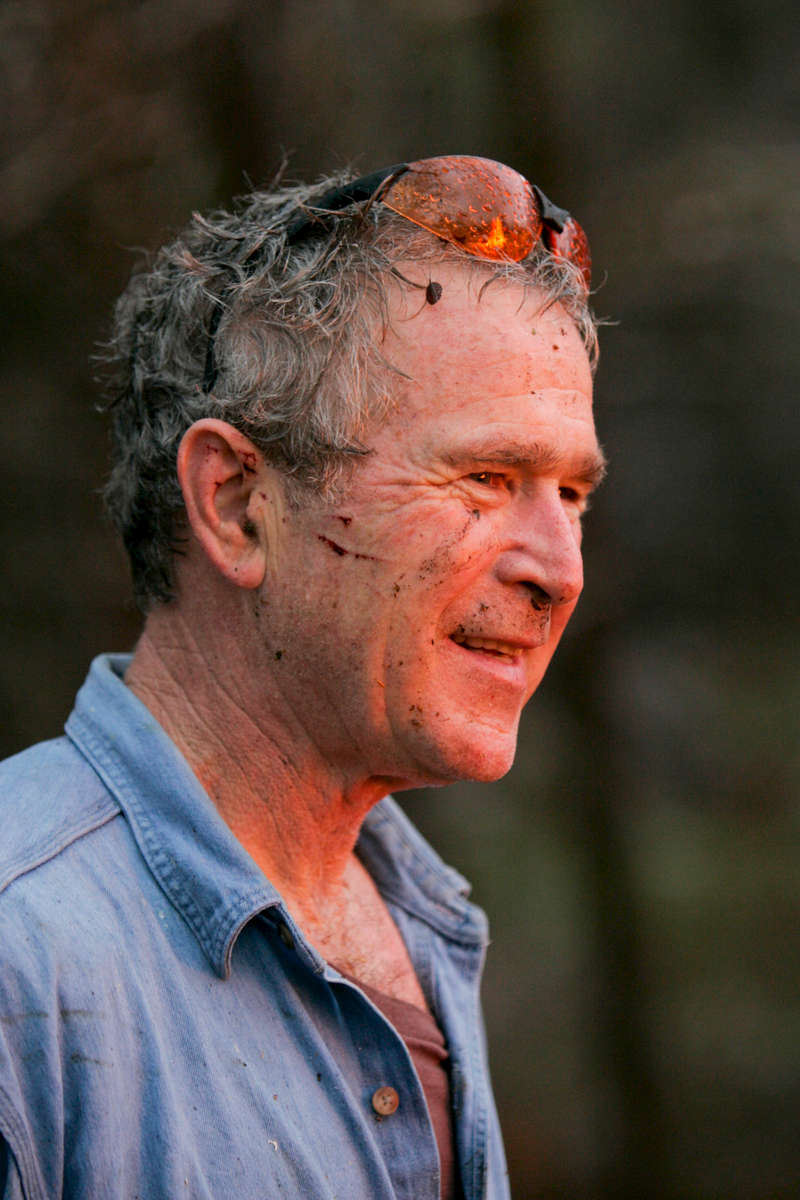 President Bush: Brush clearing and burning with staff. Ranch, Crawford, Texas. View of fire. Fire reflected in the President's protective glasses. POW