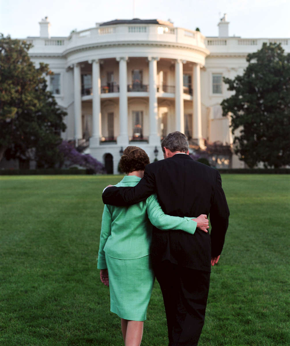 PRESIDENT BUSH AND LAURA BUSH HOLD HANDS AS THEY WALK ACROSS THE SOUTH LAWN TOGETHER DURING A PORTRAIT SESSION. THEY ARE ACCOMPANIED BY BARNEY AND SPOT. THE BUSHES POINT TO SPOT TO GET HER OUT OF THE PICTURE. THE BUSHES ARE PICTURED WITH THEIR ARMS AROUND EACH OTHER (SHOT FROM BEHIND).  MRS. BUSH TALKS ALONE WITH PHOTOGRAPHER SUSAN STERNER.RESTRICTEDLocation: SOUTH LAWN Bush Family Scrapbook 4.16.02-4.30.02