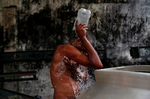 Jose Angel Salinas of Honduras bathes near a park as his fellow migrants, part of a caravan traveling to the U.S., rest in the park in Huixtla, Mexico.