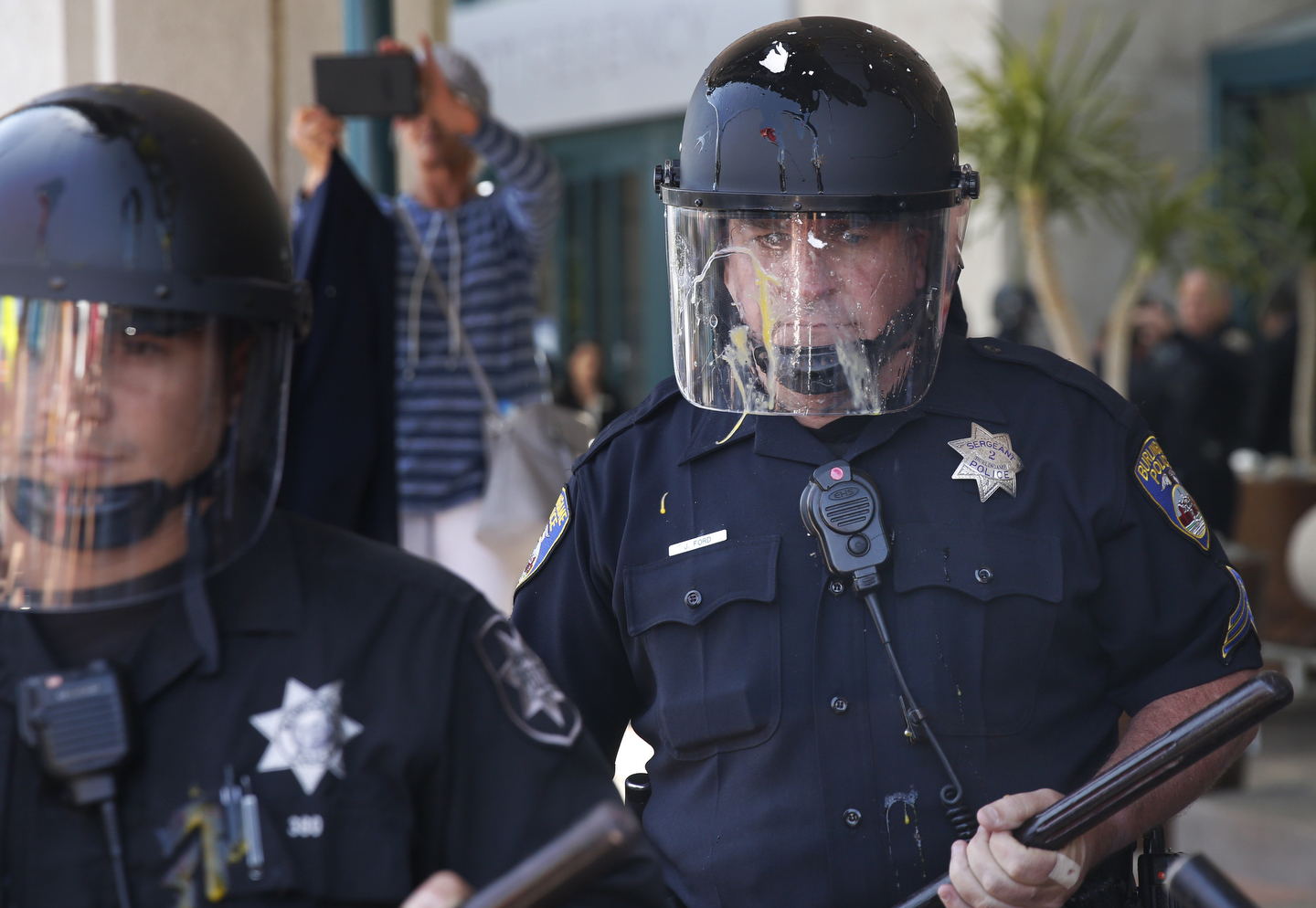 An egg that smashed onto a police officer's face shield runs as he stands between protesters and the front of the Hyatt Regency during the first day of the California Republican Party Convention which featured speeches from Presidential candidates Donald Trump and John Kasich among others April 29, 2016 in Burlingame, Calif.