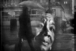 Pedestrians walk up and down Broadway Ave. in the rain as seen in a reflection on an ad featuring Maya Angelou Jan. 3, 2016 in downtown Oakland, Calif.
