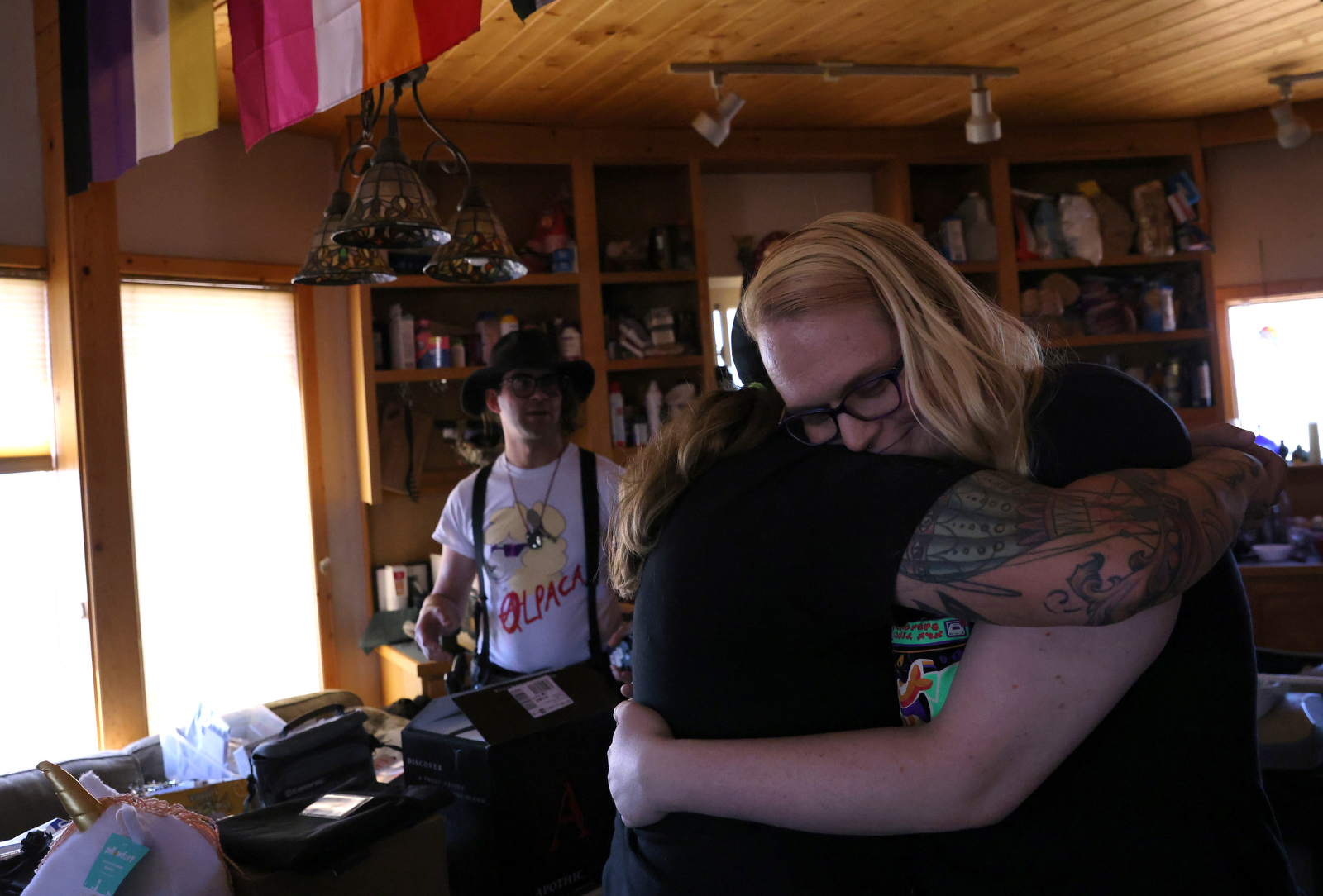 Penny Logue hugs one of her partners, Kathryn Gibes in their home.