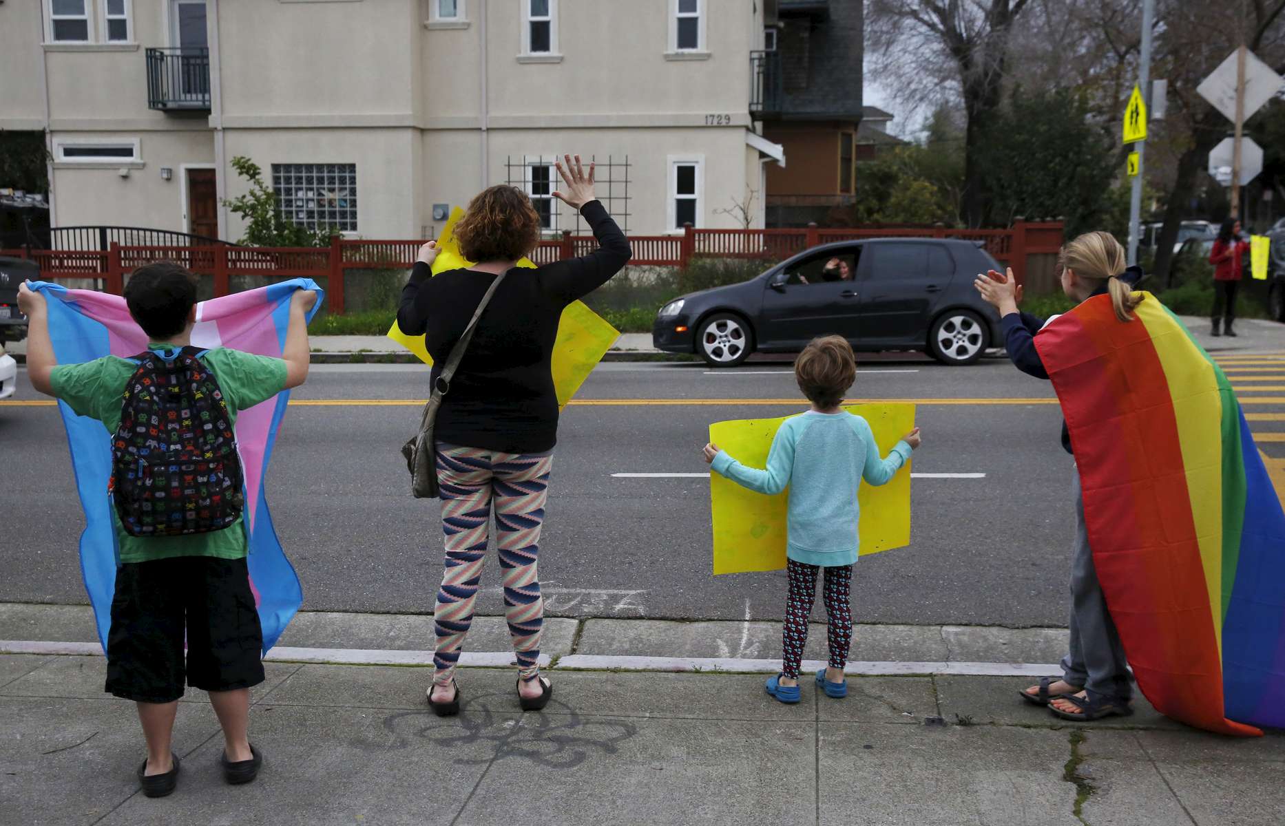 From left, James, 9, Sara and Charley Kaplan, 4, hold signs and cheer with other students and parents at a rally for Gavin Grimm organized by Sara outside of Malcom X Elementary School Feb. 15, 2016 in Berkeley, Calif. Grimm, a transgender teenager, sued the school board of his Virginia high school for the right to use the bathroom that corresponds with his gender identity. Sara Kaplan organized a rally that was one of many coordinated across the nation in support of Grimm before his case was to be seen by the Supreme Court.