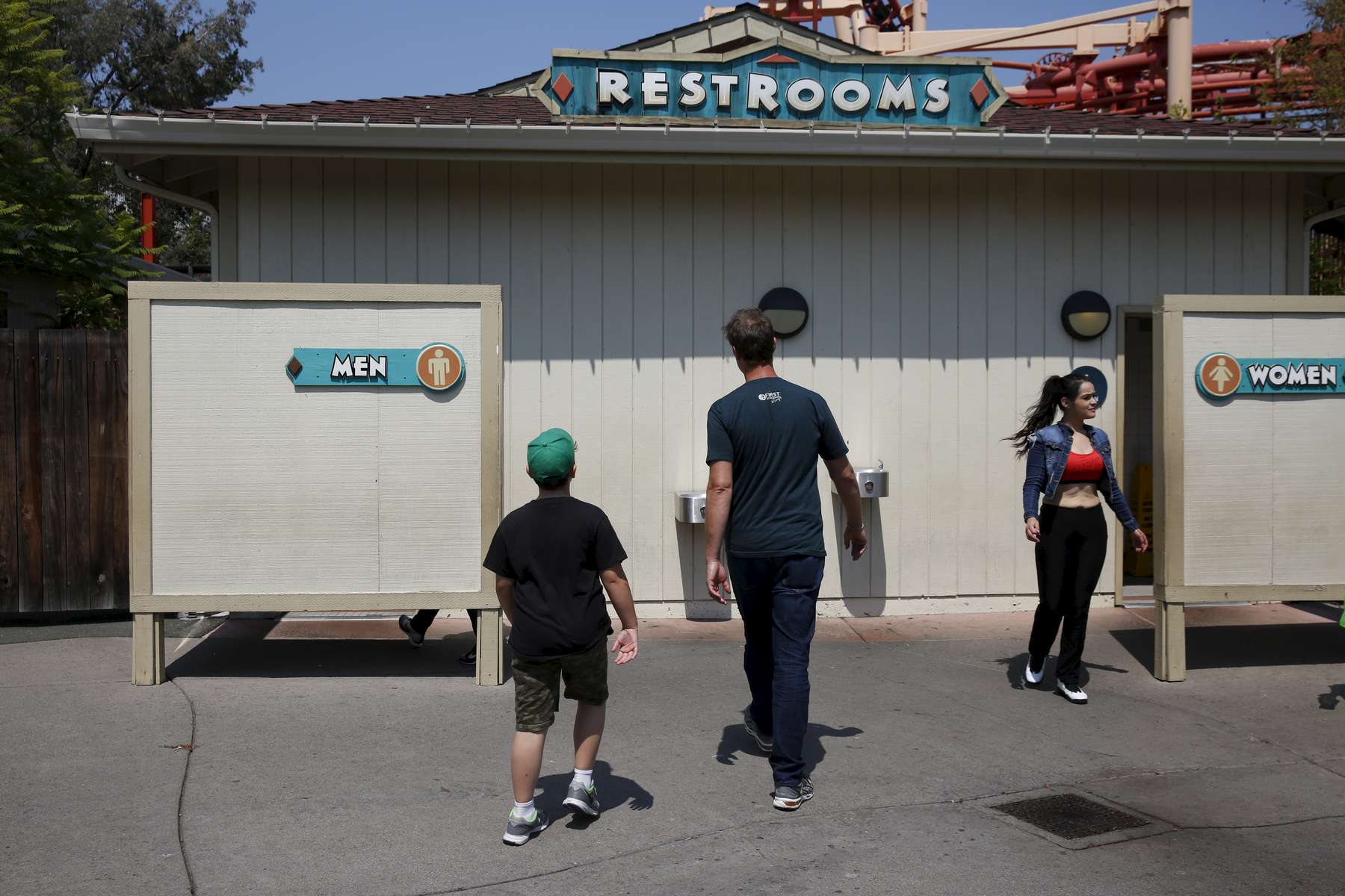 James, 8, and Ben Kaplan walk towards the men's bathroom together while enjoying a family outing to Six Flags amusement park Aug. 20, 2016 in Vallejo, Calif.