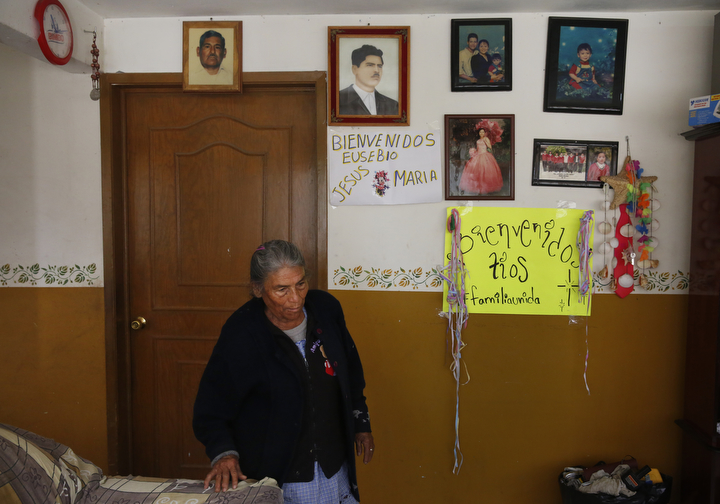 Eusebio's mother, Guadalupe Mejia Sanchez, 78, walks past welcome home signs for Eusebio, Jesus and Maria posted in her living room Sept. 27, 2017 in Santa Monica, Hidalgo, Mexico. The signs are leftover from about a month previously, when the three first arrived in Mexico after they were deported from Oakland.