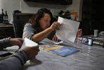 Vianney Sanchez, 23, center, shows her mother Maria Mendoza-Sanchez, lower right, pictured on screen, the mail Sept. 8, 2017 in their family home in Oakland as Vianney and her sisters Elizabeth, 16, left, and Melin, 21 (not pictured) video chat with their mother as she lays in her bed in Mexico. Though she is thousands of miles away, Maria does her best to stay highly involved in her daughter's day-to-day lives. Maria must also continue to pay her mortgage and other bills.