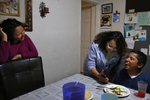 Jesus Sanchez, 12, laughs at a viral internet video with his sisters Vianney, 23, center right, and Melin, 21, left, while eating his favorite meal prepared by Vianney after arriving back to their Oakland home from the airport and Mexico Oct. 14, 2017 in Oakland, Calif. Their mother Maria Mendoza-Sanchez made the decision to send him back to the US after it was discovered that his paperwork hadn't gone through quickly enough for school and he would have to repeat the entire grade over again.