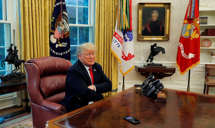 U.S. President Donald Trump looks down at a reporter's phone on his desk that is recording his words during an interview with Reuters in the Oval Office of the White House in Washington, U.S. August 20, 2018.  REUTERS/Leah Millis