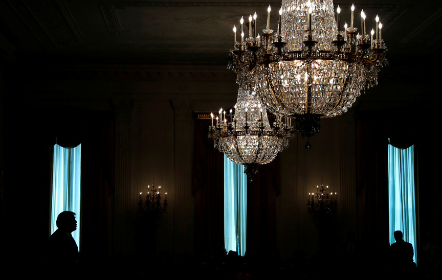 U.S. President Donald Trump is silhouetted in a window of the East Room as he participates in a ceremony awarding a Medal of Honor posthumously to Air Force Technical Sergeant John A. Chapman at the White House in Washington, U.S., August 22, 2018.  REUTERS/Leah Millis