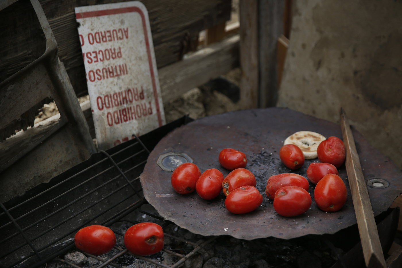 A collection of donated tomatoes lay strewn about a cooking area next to a folded sign from the landowners warning people to stay off the land outside of Mario Rodriguez's home in the shantytown. More than 40 percent of about 11,500 people in Mendota live below the poverty line. 