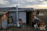 As evening falls in the shantytown, Edgar Torres Castro, 40, paints the outside of his home. Castro likes to save books from the trash and also plants various fruit trees around the encampment. He says that God told him to live out in the shantytown. 