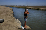 Sandoval washes her face and hair in the nearby irrigation canal. The canal is the only source of water for the shantytown residents if they want to bathe, cool down, or wash their clothing. They have to buy water from a nearby store in town for drinking and cooking.