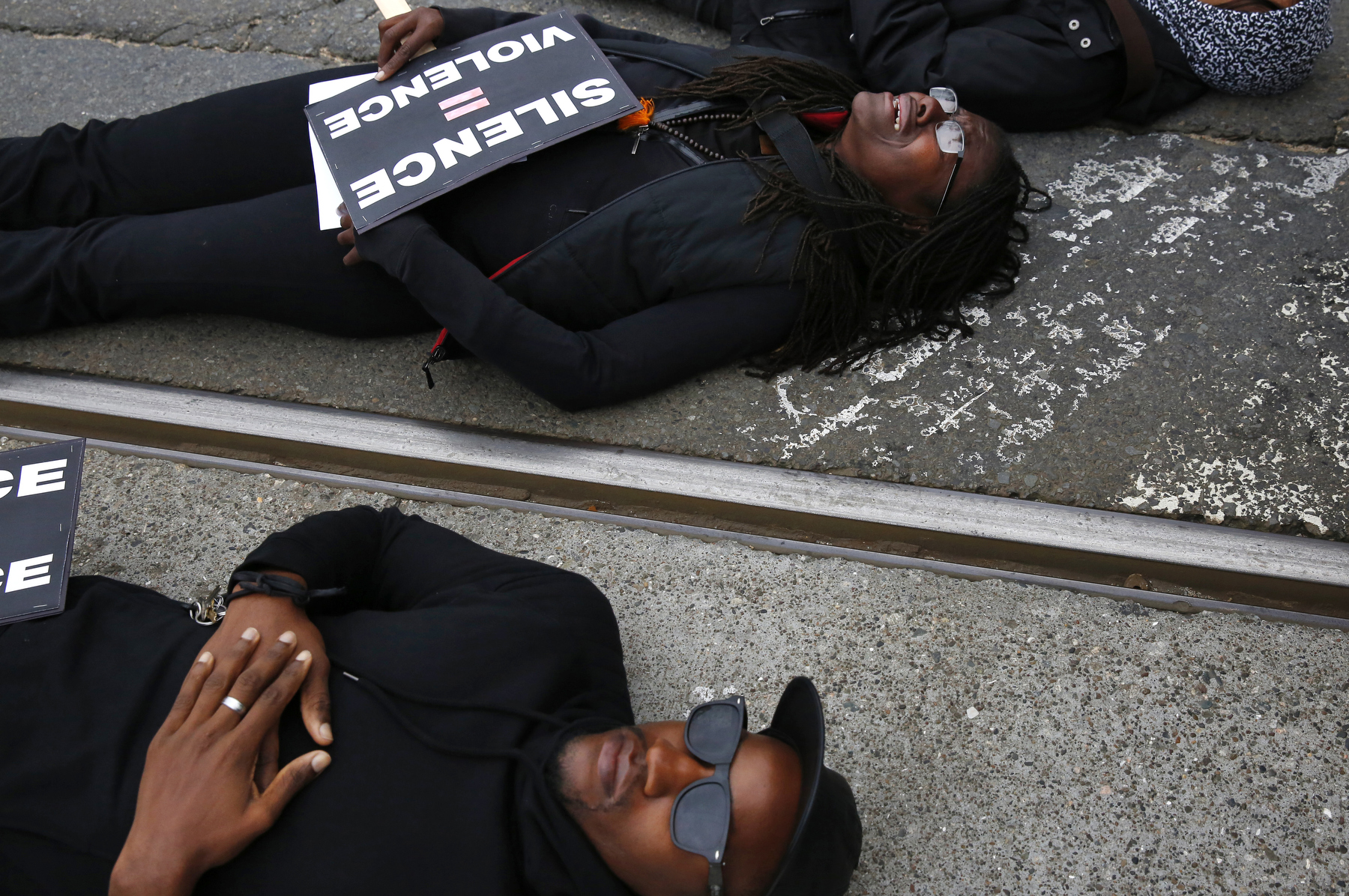 From left, Sampson McCormick, Kin Folkz and Puck Lo lay in the street as they observe four and a half minutes of silence while blocking the 101 south freeway entrance and exit ramps at the intersection of Octavia and Market streets during a {quote}LGBT Rally and March for an End to Police Violence{quote} Dec. 24, 2014 in San Francisco, Calif. 
