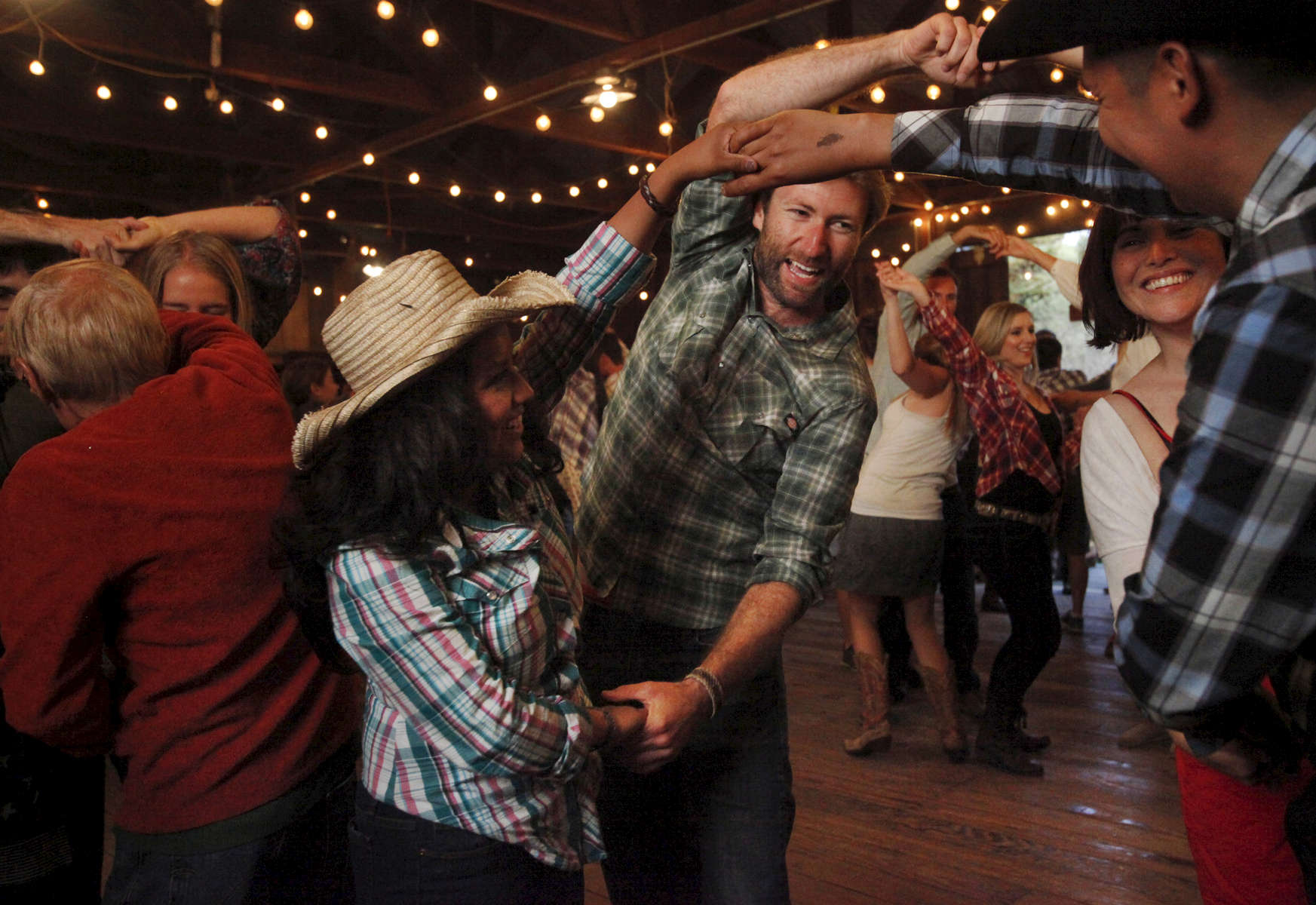 From left, Birza Santiago, 26, Brian Boyce, 30, Stacey Garcia, 31, and Jesus Jocobo, 37, laugh as they do a group dance move together during the monthly barn dance May 17, 2014 at Pie Ranch in Pescadero, Calif. Every month, the educational farm holds a work day and welcomes people to volunteer at the farm. Afterwards, people gather for a potluck and then an evening of traditional barn dancing with a caller and a live band. Margaret More has been attending the dance for eight years, she says she enjoys the intergenerational aspect and added, {quote}it feels like [we've] stepped back 150 years in civilization.{quote} 
