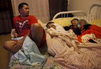 Red Rodrigo glances over at his two daughters, Brennelyn, 8, right, and Bryanna, 11, as they sleep in the bed he and his wife (their mother) sleep on in the living room in their transitional apartment Oct. 21, 2014 in San Francisco, Calif. Because the children grew up sleeping together, sometimes all five in one bed, the two youngest still like sleeping with their parents. The Rodrigo family has been living in transitional housing for almost a year after staying with a large number of family members in a very small apartment. The family hasn\'t really had a place of their own and have enjoyed having the apartment to themselves but their time allotted in the place is almost up. 