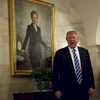 U.S. President Donald Trump greets White House visitors below a portrait of Hillary Clinton.