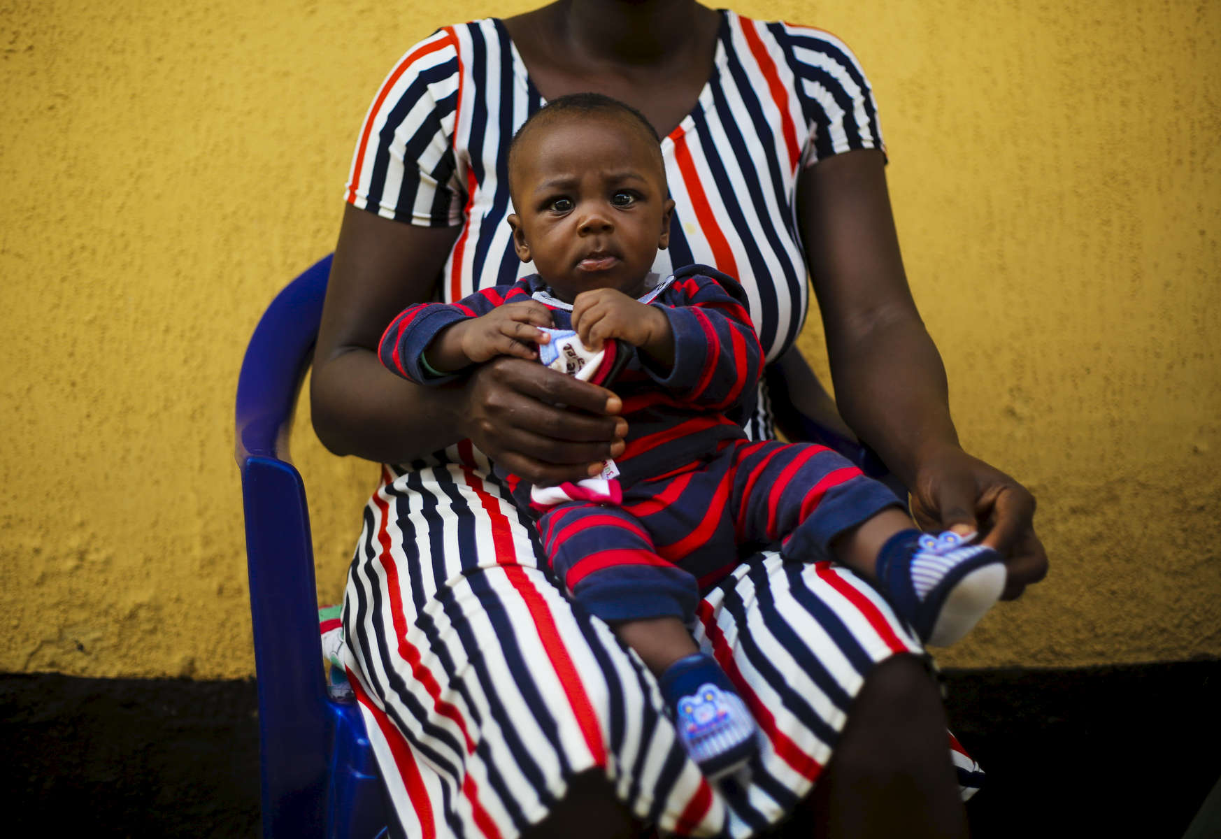 Sitting on his mother's legs, Andrew, 9 months, waits for his vaccination at the medical facility  of Kuchigoro  in Abuja, Nigeria. 