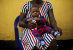 Sitting on his mother's legs, Andrew, 9 months, waits for his vaccination at the medical facility  of Kuchigoro  in Abuja, Nigeria. 