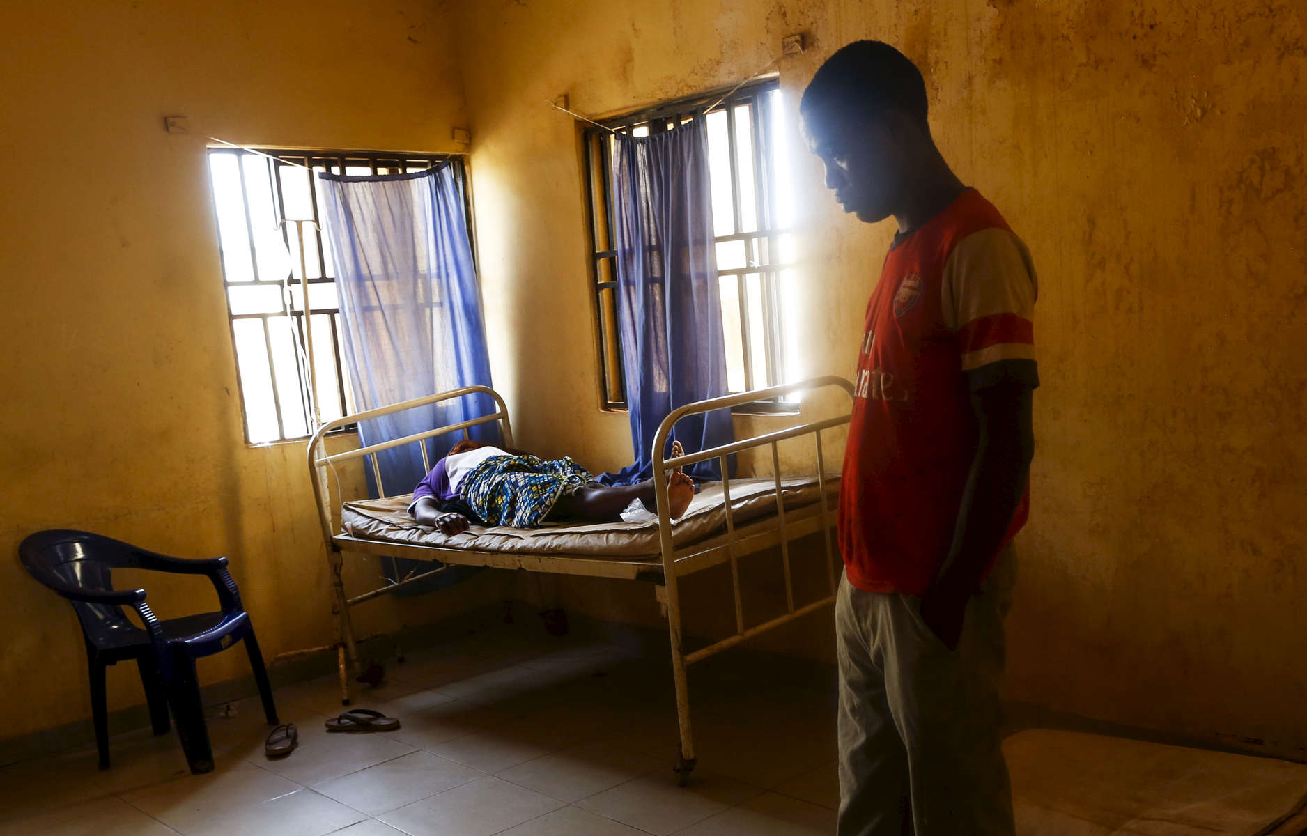 A pregnant woman rest on a bed as she is having bleeding while her husband reflects at the medical facility of Kuchigoro in Abuja, Nigeria.