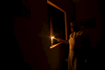 Nurse Williams light a candle at night during a power outage at the medical facility of Kuchigoro in Abuja, Nigeria.