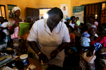 Nurse Christy Anya prepares medecine while patients in a packed room wait for appointment. 