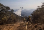 A firefighting helicopter makes a water drop on flames from the Alisal fire, while firefighters work on a hot spot in Aguajito Canyon near Santa Barbara, California, U.S., October 14, 2021.  