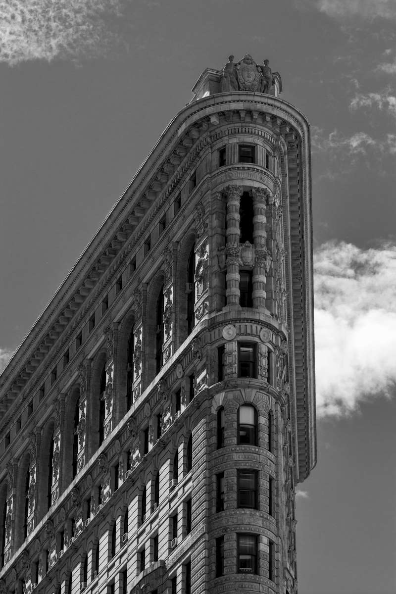 The Flatiron Building, originally the Fuller Building, is a triangular 22-story steel-framed landmarked building located at 175 Fifth Avenue in the borough of Manhattan, New York City, which has been called {quote}one of the world's most iconic skyscrapers and a quintessential symbol of New York City.{quote}