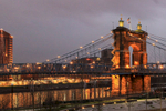 The John A. Roebling Suspension Bridge, originally known as the Cincinnati-Covington Bridge spans the Ohio River between Cincinnati, Ohio and Covington, Kentucky. When the Roebling Bridge was formally opened on January 1, 1867, it was the longest suspension bridge in the world at 1,057 feet (322 m) main span.  When it opened, the driver of a horse and buggy was charged a toll of 15 cents to cross; the toll for three horses and a carriage was 25 cents. Pedestrians were charged one cent.The bridge was designated a National Historic Landmark in 1975 and was designated a National Historic Civil Engineering Landmark in 1983. It remains the busiest of Cincinnati's four non-freeway automobile or pedestrian bridges. Initially called the {quote}Covington-Cincinnati Suspension Bridge{quote} or {quote}Ohio River Bridge{quote}, it was renamed in honor of its designer and builder on June 27, 1983This image was taken from the Smale Park Riverfront Park, a 45-acre park on Cincinnati's downtown riverfront situated between Great American Ballpark and Paul Brown Stadium