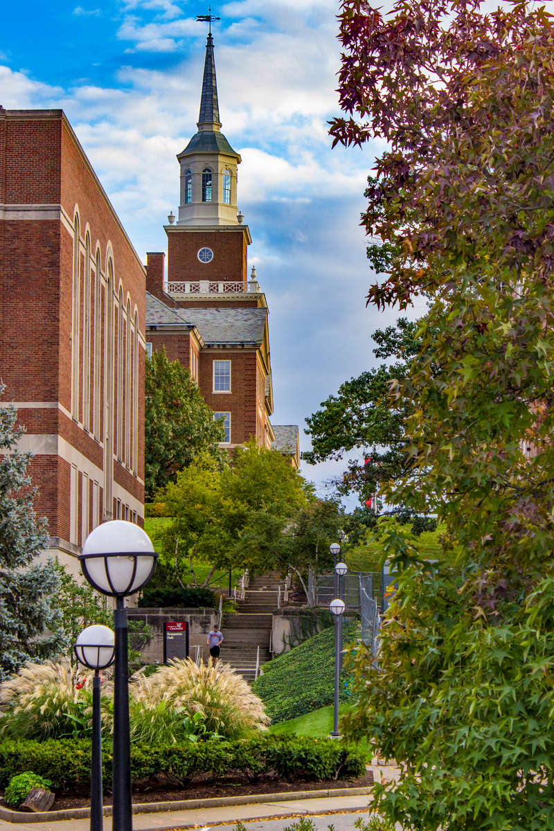 Old McMicken Hall was designed by famed Cincinnati architect Samuel Hannaford, The cornerstone of McMicken Hall, at its new site on the former Burnet Woods park, was laid on September 22nd, 1894 and the building was completed in September of 1895.  The architecture was of Neo-Georgian design in an effort to connect the university with other universities in the country and evoke feelings of patriotism and academia.  The old McMicken Hall would remain standing until the late 1940s when it was razed in order to build a new hall in the same location.  Dedicated in April 1950, the new (and current) McMicken Hall was of similar design to old McMicken.  Designed by another famed Cincinnatian, architect Harry Hake, the hall maintained a Georgian style, repeating the two flanking wings of the previous building and even including 650,000 bricks from old McMicken.  It was intended to resemble the student Union (now Tangeman University Center), which was completed in 1937.  This image is a view seen exiting the DAAP building, from a lower elevation facing south.