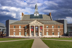  In the center of West Campus is Tangeman University Center.  Architects Harry Hake and Harry Hake Jr. built TUC in 1937 in response to a growing student population.  The building was constructed with a Georgian Colonial style and highlighted by the large columns at the entrance and the clock tower.  The image of TUC's clock tower has been utilized on countless materials showcasing the campus of the University of Cincinnati. The clock and the Brown Memorial Chimes within the tower were donated in recognition of UC alumni Sanford Brown.  Brown contributed to the campaign to secure funds for building TUC and with his tireless effort, funds from the Public Works Administration and the city of Cincinnati, ensured that the student Union could be built.  TUC was known originally as the Student Union or simply as the “Union.”  At the time of its construction, it was one of the two largest buildings on campus and it housed the majority of the student organizationsAs the student population continued to grow additional space was added on the Student Union in 1967 at a cost of approximately 3.6 million.[10]  Funds were raised for the construction through a special fee students agreed to pay.  Charles Gwathmey’s firm designed the Tangeman University Center at the U. of Cincinnati.  The design preserved a red-brick facade, along with a clock tower, and grafted on a metal-shrouded addition. After construction; Student Union was renamed in honor of Donald Core Tangeman, the son of University of Cincinnati alumni.[12]  The addition nearly doubled the size of the TUC providing more areas for student activities.[13] Between 2001 and 2004, renovation became necessary to bring the building up-to-date and TUC underwent a major transformation[14].  Additions were added on both sides of the building and the 1967 addition was removed.[15]  Once reopened, students were able again to congregate, eat lunch and buy books, while the new amenities of TUC allowed students to see movies at the MainStreet Cinema or engage with fellow students in the Catskeller Game & Sports Lounge.[16]  Although it has undergone many changes, Tangeman, at its core, remains a place for students.