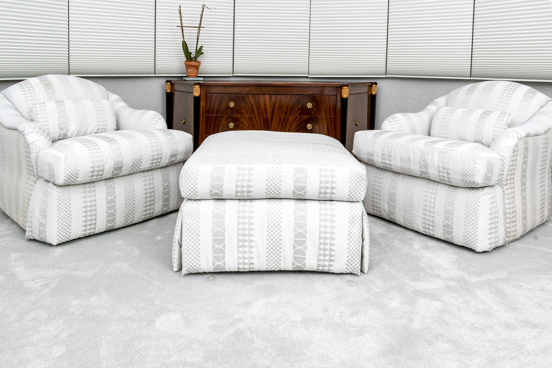 A luxurious pair of club chairs with an ottoman, designed by Sally Sirkin Lewis for J. Robert Scott, features oversized and comfortable designs. The chairs have low, arched backs and rolled, curved arms that flank deep-set seats, all resting on tall, thick skirts. They are upholstered in a chic white and gray fabric adorned with patterned stripes, including circular, checkerboard, and triangular designs.Chairs: 32{quote} H x 34{quote} L x 34” DOttoman: 19{quote} H x 32{quote} x 32”List Price $9,000 / Our Price $4,000