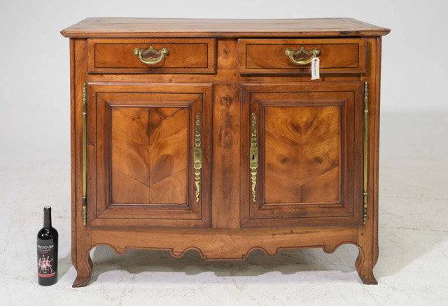 This French country-style furniture features a molded rectangular top, two upper drawers, and paneled sides. It is finished with a scalloped apron and adorned with brass hardware. The piece showcases a rich, deep amber patina. 49” x 24” x 39.5”Our Price $2,250