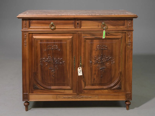 This sideboard features a beautifully carved walnut body, intricately adorned with floral and foliate designs, as well as ribbons and bows. It includes two smoothly sliding drawers above two doors, which open to reveal four additional drawers, providing ample storage space.48.5” x 21” x 41”Our Price $2,800