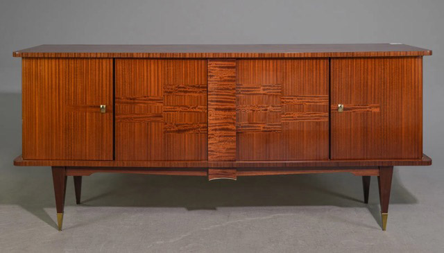 This sideboard, or credenza, features a stylish bar cabinet and showcases beautiful Macassar wood grain with a striking pattern. It offers ample storage space with multiple shelves. The case is supported by tall, tapered legs embellished with brass details, creating a unique blend of Art Deco and Mid-Century Modern design.86.75” x 21” x 38”Our Price$ 5,200