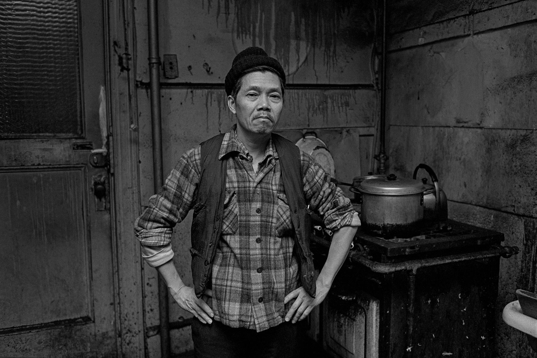 A man stands in the kitchen of the Bachelor Apartment where he lives with 3 other men in New York Chinatown in 1982.