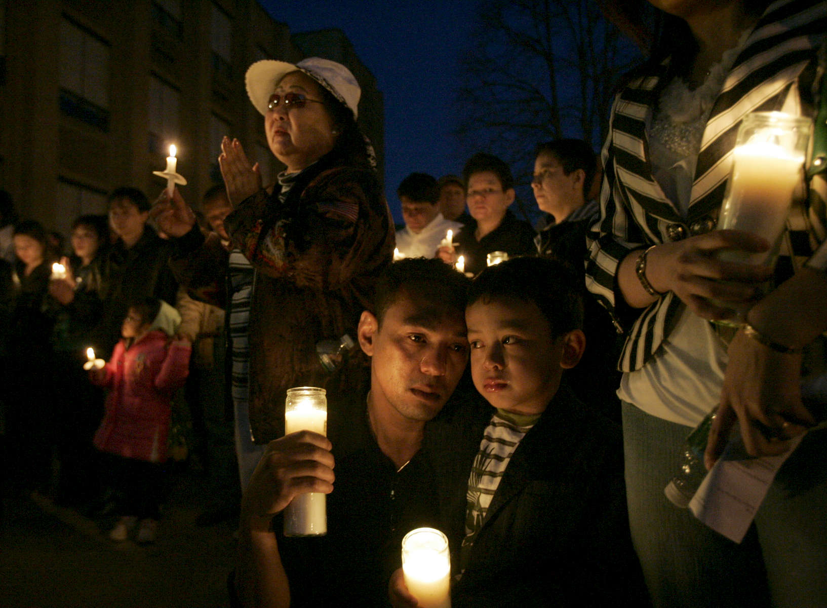 Thirteen people were killed after a gunman open fire inside American Civic Association before taking his own life in Binghamton, New York. Minh Nguyen, 38, and his son Henry, 6,  relative of Lan Ho, one of the 13 people who were killed, weep as they remember Lan at the candle light vigil held at West Junior High School at West Middle Avenue in Binghamton, New York on April 05, 2009.  