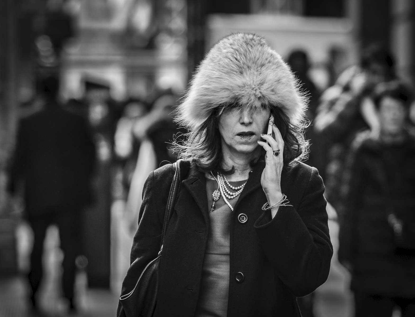 A woman in a fur hat talks on her phone and walks along 6th Avenue in Midtown, Manhattan on February 11, 2017. 