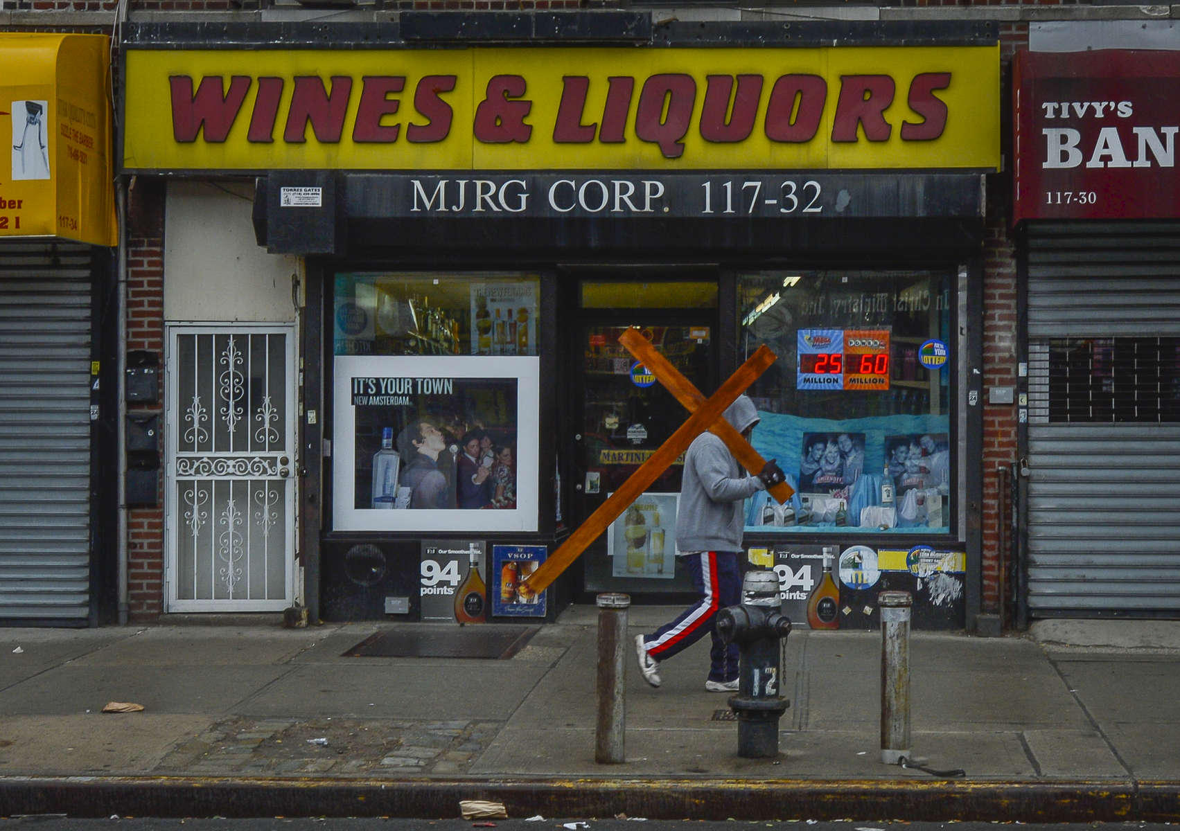 An unidentified man carries a cross as he walks past a Wines & Liquors store along Sutphin Boulevard in Jamaica, Queens on Good Friday, April 3, 2015. Good Friday is a Christian religious holiday commemorating the crucifixion of Jesus Christ and his death at Calvary.