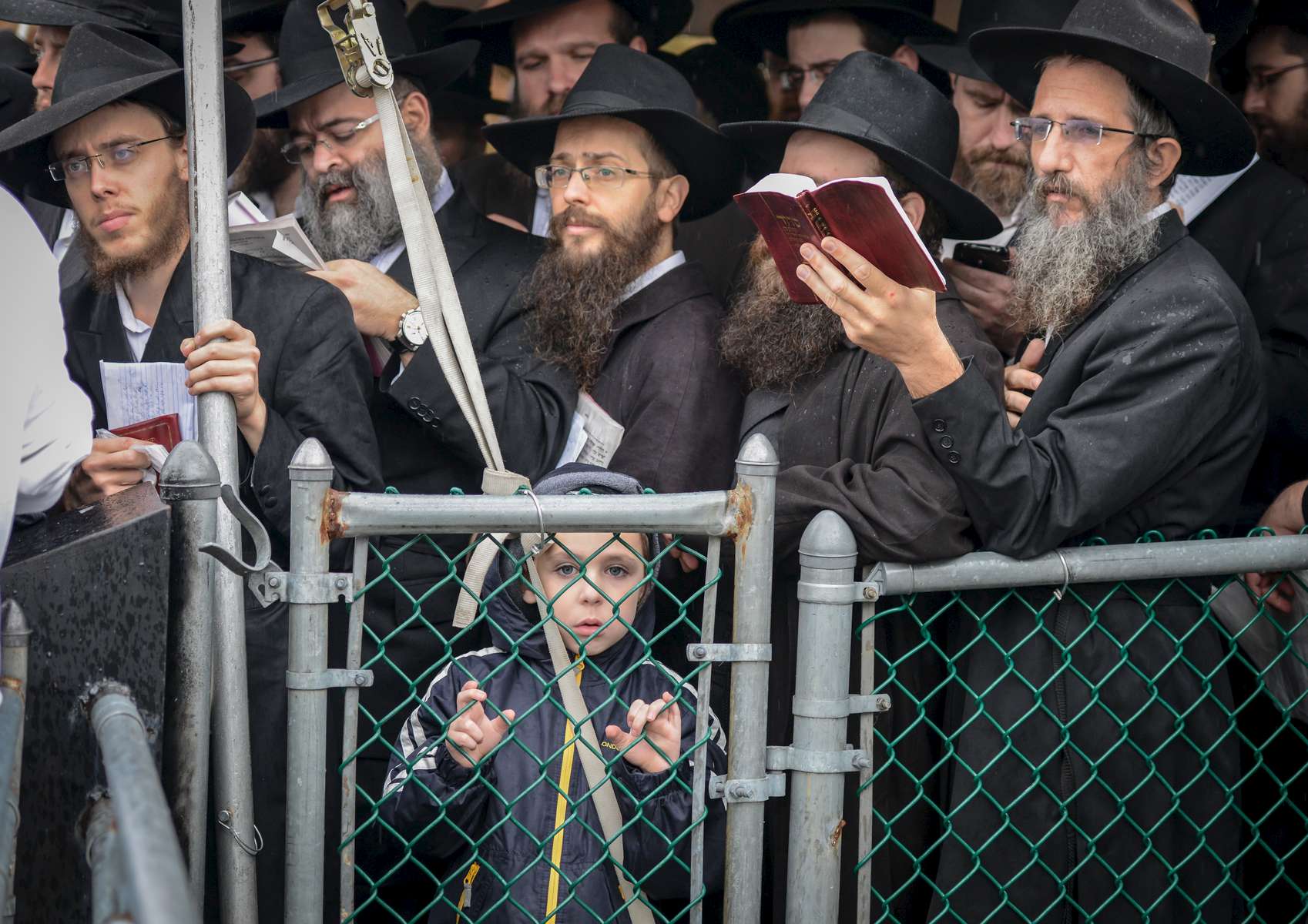 A kid looks on from behind the fence as he joins rabbis from around the world wait on line to pray at the gravesite of the Labavitcher Rebbe, Rabbi Manachem M. Schneerson at Old Montefiore Cemetery located at 226-20 Francis Lewis Boulevard in Queens on Friday, November 1, 2013. Rabbis from around the world meet in New York for the International Conference of Chabad-Lubavitch Emissaries, an annual event aimed at reviving Jewish awareness and practice around the world.