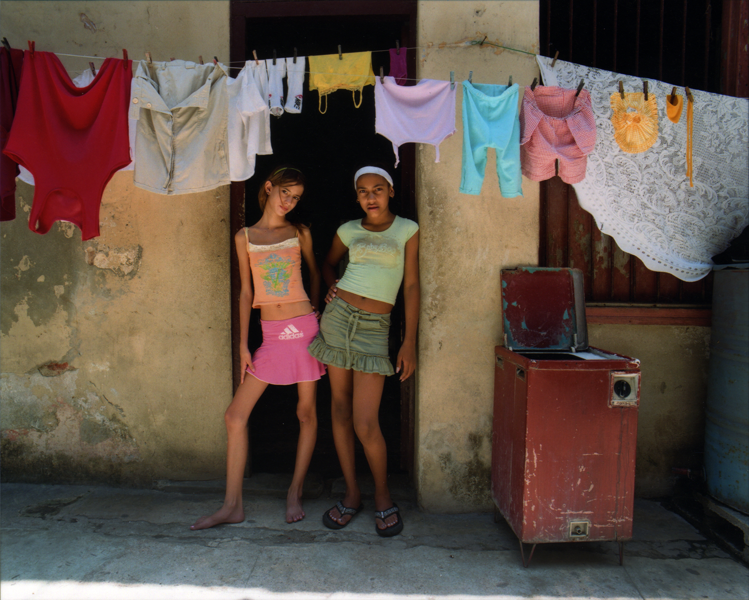 Two girls washing and hanging the clothes to dry, stop their work to have their porttaits taken. Havana, Cuba