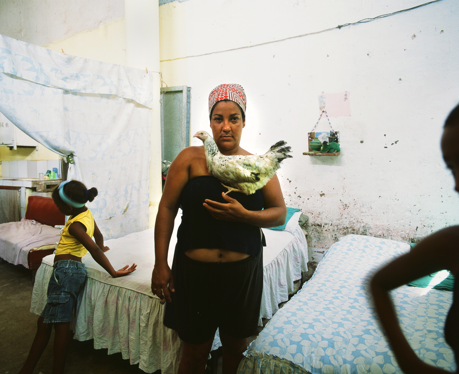 Lelani holds her pet chikcen while her two daughters, Kailey (left) and Hamilie (right), play in their home. Havana, Cuba