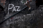 A youth jumps down a stairway with the word {quote}peace{quote} written on the wall, in the Shantytown of Rocinha, the biggest slum of Rio de Janeiro, Brazil, February 22, 2012.Initiated in 2008, the UPP, short for Unidade de Polícia Pacificadora (in English, Pacifier Police Unit or Police Pacification Unit), is a new system of community policing in Rio de Janeiro’s favelas once run by drug traffickers. While many believe that UPPs have helped quell violence by opening the doors of the favelas to public services such as legal electricity supply, garbage collection, education, public works and social assistance program, others see the pacification program as a temporary cover-up to security problems in Rio de Janeiro. 