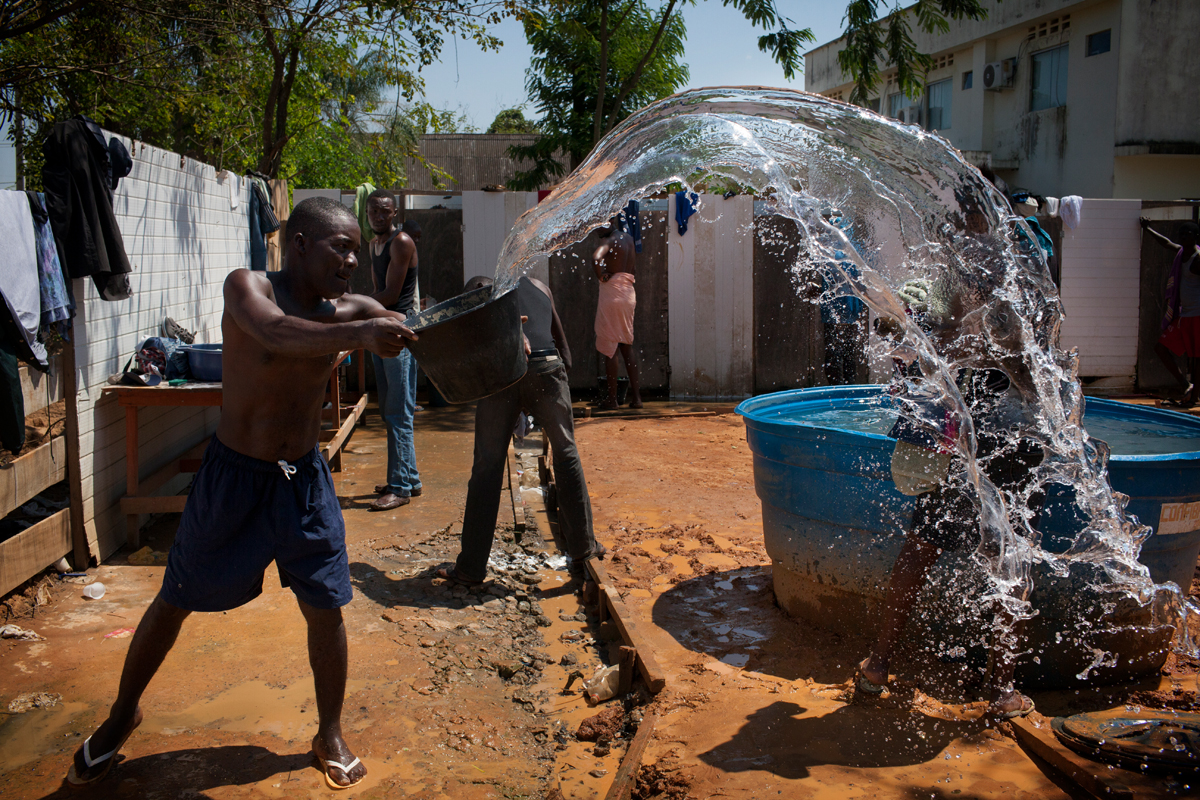 A man throws a bucket of dirty water before having a shower in the refugee camp of the State of Acre, in Brasileia, Brazil, September 28th, 2013.