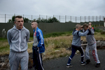 Young people near a so-called peace wall in north Belfast separating the Protestant Glenbryn area from the Catholic Ardoyne area on the other side. {quote}Taking peace walls away is not going to take bitterness away{quote} said Michael (left), 19. {quote}The walls prevent a clash, the bitterness bounds off on them. They shouldn't come down over the next 100 years, there's still too much pain. Belfast is still totally a divided city.{quote}First built in 1969 as a temporary solution to reduce violence, the peace walls — a euphemism for segregation barriers — have increased in number and scale since the start of the peace process. The barriers take many forms: Not only walls but also fences, gates, roads and empty buffer zones divide the Catholic and Protestant communities in some of the city's most economically deprived areas. The government promised to take the barriers down by 2023, but many residents are not ready for them to come down any time soon. Not all interface areas — the common boundary between a Protestant and a Catholic area —  have a physical border. Sometimes there is only an invisible dividing line that local people are aware of.