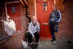 Ashley, 26, smokes a cigarette outside her home while her boyfriend's brother Dylan, 16, stands next to her in the Protestant Lower Shankill estate in west Belfast. Ashley's family was heavily involved in the UDA (Ulster Defence Association), a loyalist paramilitary group. During the feuds among different factions of the UDA in 2001 her family was expulsed by another faction and they now live in England. After some time Ashley and her mother were allowed by the paramilitaries to come back.