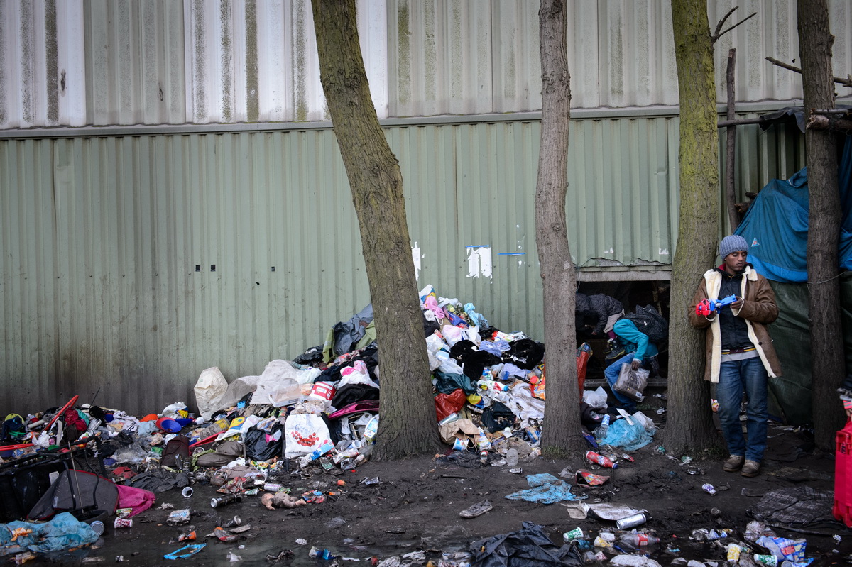 Calais, December 2014 A man stands in front of the sole entrance to a hangar housing hundreds of migrants in the Tioxide jungle, the main migrant camp situated next to a chemical plant.